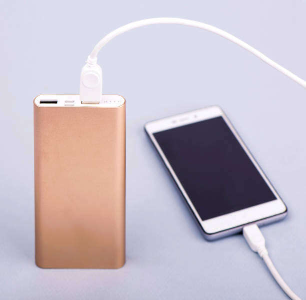 istock Smartphone charging with power bank and phone on gray background 1296109784