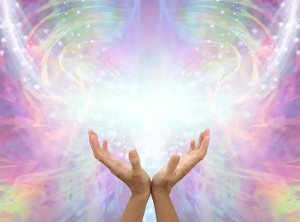 female cupped hands reaching up into an Angelic shimmering sparkling  pink ethereal energy background with copy space