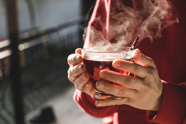 Woman holding hot tea with both hands in cold weather. A cup of tea is steaming. stock photo