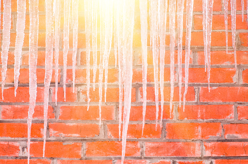 Icicles hanging against a background of red brick wall