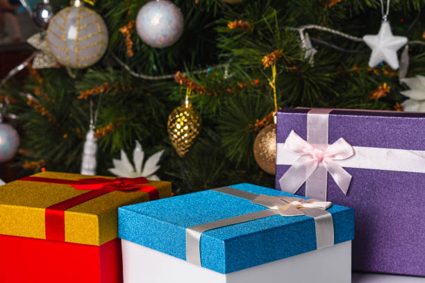 istock Gift boxes with ribbons with a Christmas tree in the background 1296116955