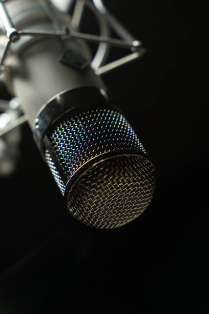 Close up of professional microphone with color gradient on it, against black background.