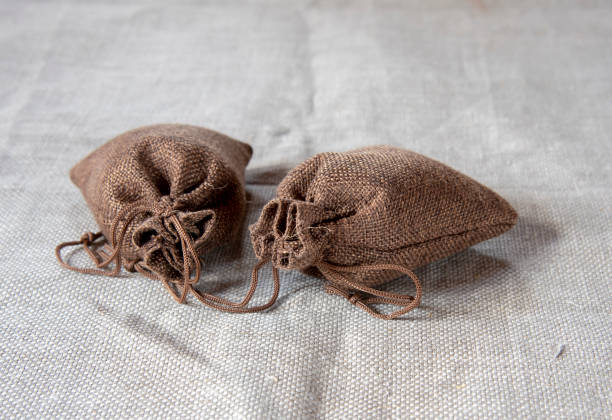 Two brown canvas bags with ties on a gray linen cloth.