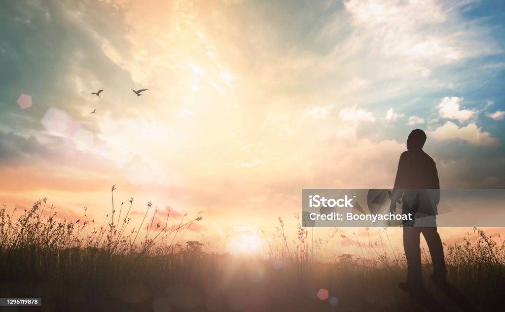 Worship and praise God concept Worship and praise God concept: Silhouette humble man standing on sunlight with meadow autumn sunset background Mental Health Stock Photo