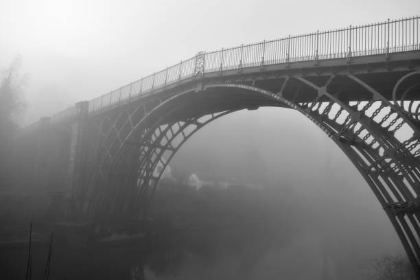 black and white image of the Ironbridge, Shropshire, UK on a misty morning spanning the river severn. The bridge is enveloped in fog giving an eeriness on a winter day ironbridge shropshire stock pictures, royalty-free photos & images