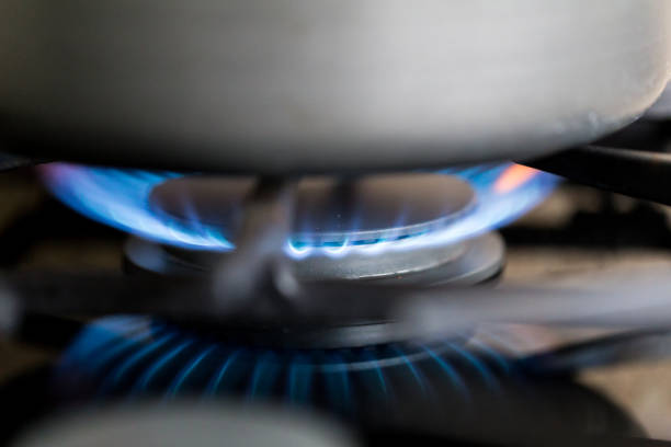 Close up macro color image depicting blue flames burning on a gas hob in the kitchen.