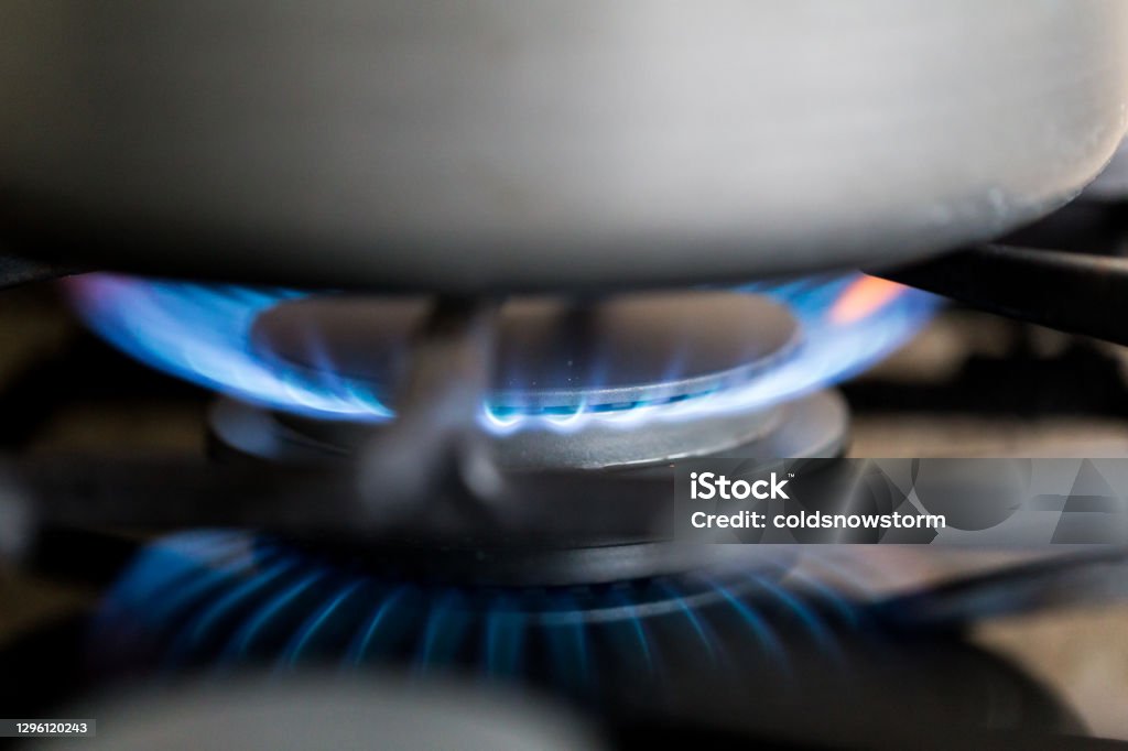 Gas hob in the kitchen with blue flames burning Close up macro color image depicting blue flames burning on a gas hob in the kitchen. Gas Stove Burner Stock Photo