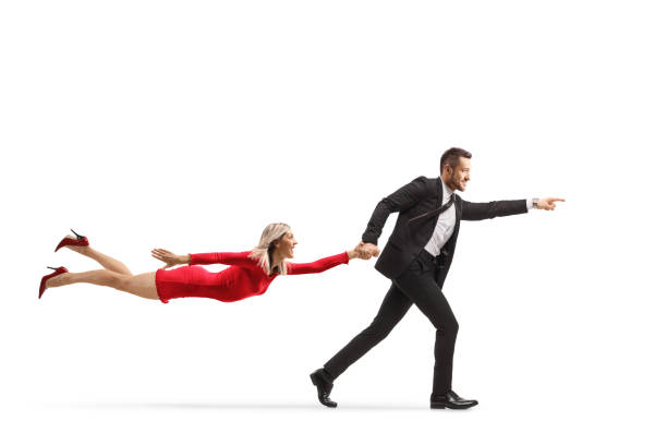 istock Man in a suit running and pulling a woman in a red dress 1296121150