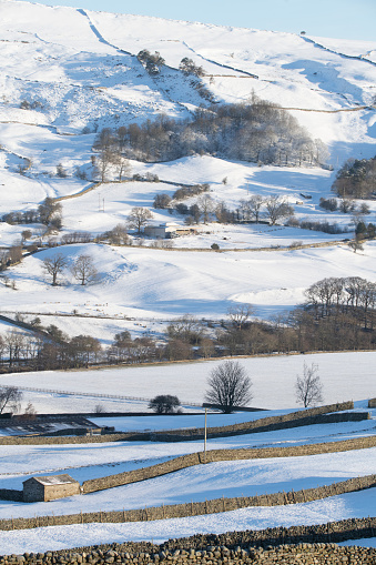 the north yorkshire dales during winter under snow showing isolated properties and drystone walls