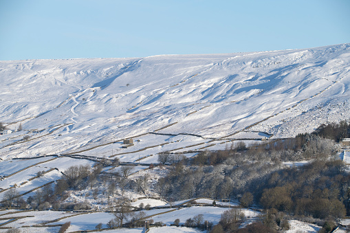 the north yorkshire dales during winter under snow showing isolated properties and drystone walls