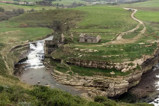 Ruins of the Bolao watermill and the falls on the cliffs in the north of spain, Cobreces, Cantabria.