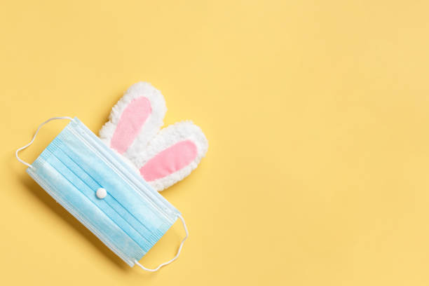 istock Easter and quarantine. Rabbit in a protective medical mask on a yellow background. 1296130762
