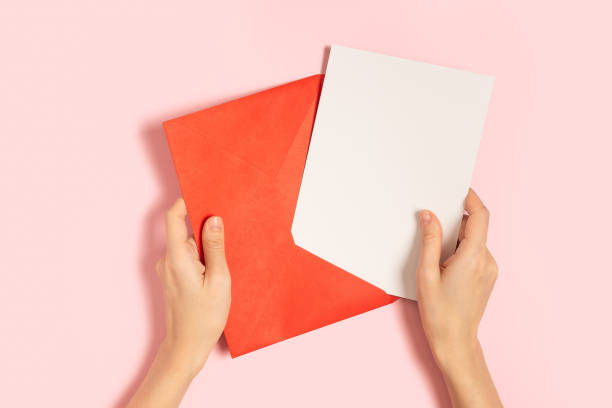 istock Blank white card with red paper envelope in hands 1296133052