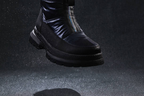 istock Fashion black unbranded boot with drops, spray and splashes flying on dark background. 1296138530