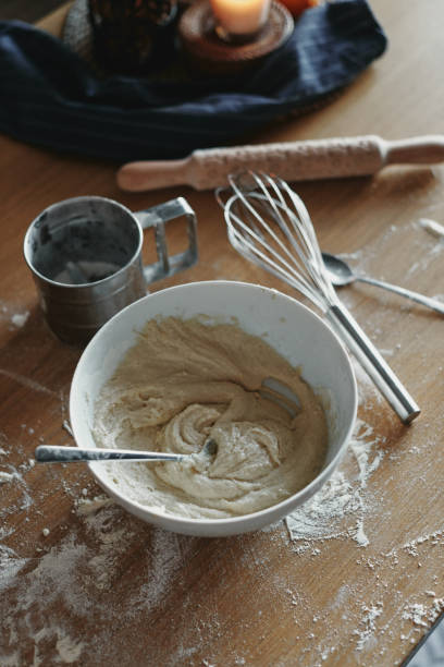 istock White bowl with dough and spoon in it, on the wooden table in the kitchen. The process of mixing ingredients for pastry. Closeup, selectiveÂ focus. 1296141205