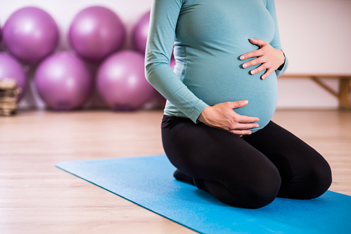 Close up stomach of a pregnant woman on exercise mat  in gym.