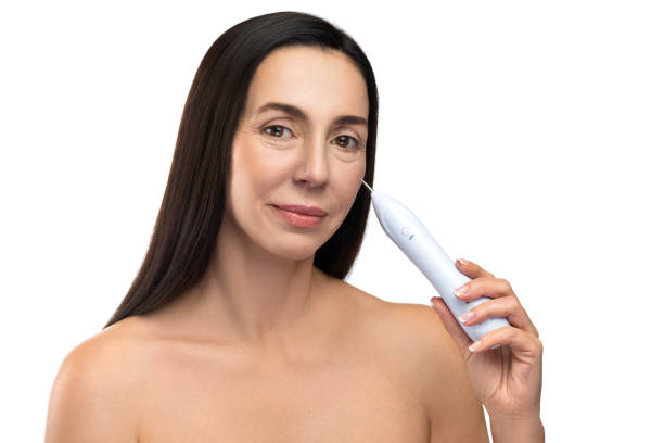 Middle aged woman using plasma pen for a non-invasive skin rejuvenation. Anti aging treatment. Middle aged woman using plasma pen for a non-invasive skin rejuvenation. blood plasma stock pictures, royalty-free photos & images