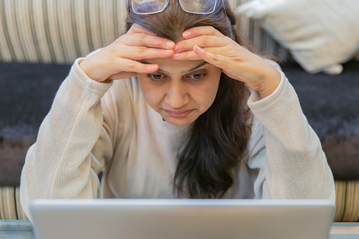 La mujer agarra su cabeza mirando el portátil. Enfoque selectivo en la cara. Educación, foto de concepto de negocio. photo