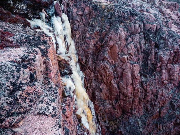 istock Frozen waterfall from a cliff. Atmospheric minimalist Arctic landscape with a hanging glacier on a rocky mountain top. 1296143043