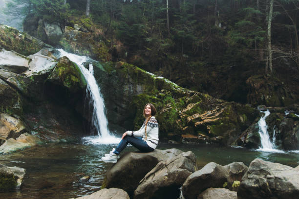 istock Young woman exploring the beautiful waterfall in the mountain pine forest 1296143261
