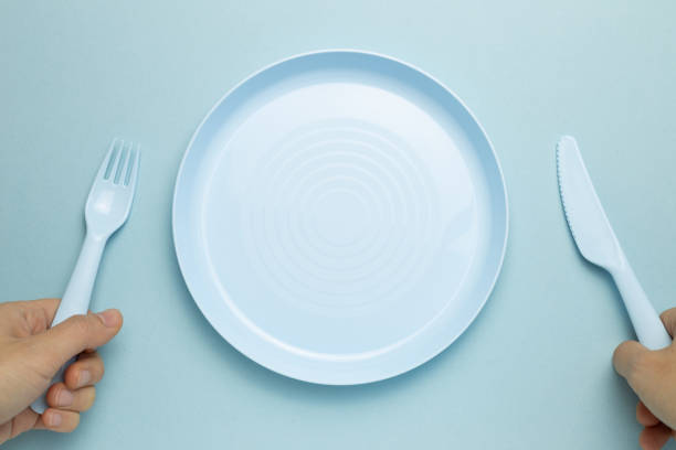 istock Fork, knife and empty plate on sky blue background. flat lay, top view, copy space 1296143392