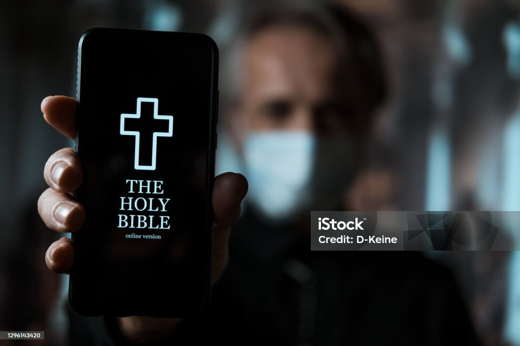 Bible online Priest holding smartphone with mobile version of Holy Bible Catholicism Stock Photo