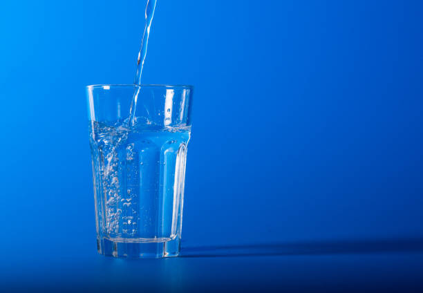 istock A glass of mineral water in studio on blue background 1296146234