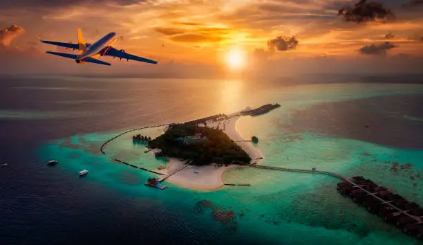 An airplane is approaching a tropical paradise island in the Maldives with turquoise during a colorful sunset