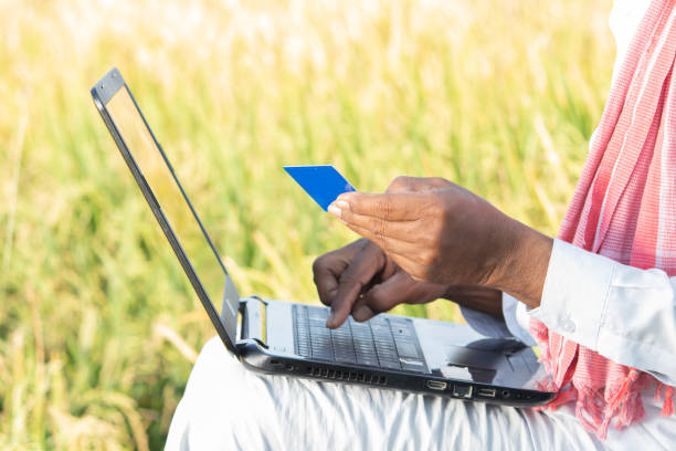 irreconocible agricultor indio en el ordenador portátil haciendo el pago mediante el uso de tarjeta de crédito - concepto de la gente rural que utiliza la tecnología, internet y estilo de vida. - farmer rural scene laptop computer fotografías e imágenes de stock