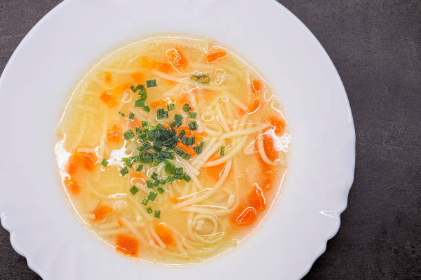 istock Vegetable broth with noodles. Homemade soup on a white plate. 1296148450