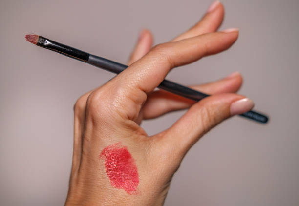 istock Hand holding a Make-up brush. Lipstick on skin 1296149350