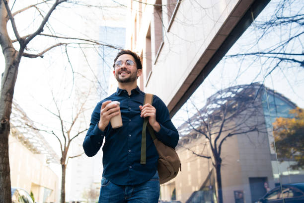 istock Young man holding a cup of coffee while walking outdoors. 1296149755