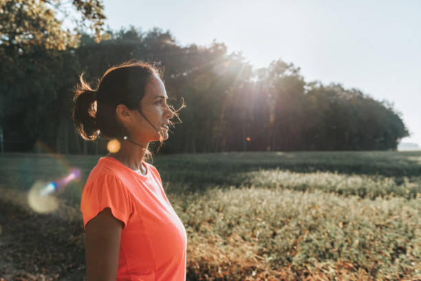 sportswoman standing in the sunny landscape profile view on sportswoman standing on path in the sunny landscape mental wellbeing stock pictures, royalty-free photos & images