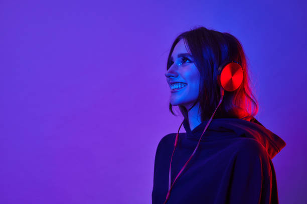 fashion hipster woman smiles and wear headphones listening to music over color neon background at studio. - musical instrument fotos imagens e fotografias de stock