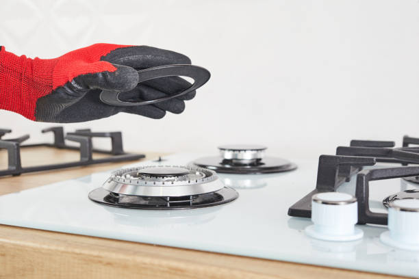 istock Worker install burner on gas hob in kitchen interior. Repairs of gas control panel. 1296149937
