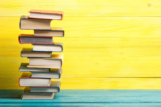 istock Books on wooden desk table and abstract yellow background. Education background. Copy Space. Back to school. 1296151123