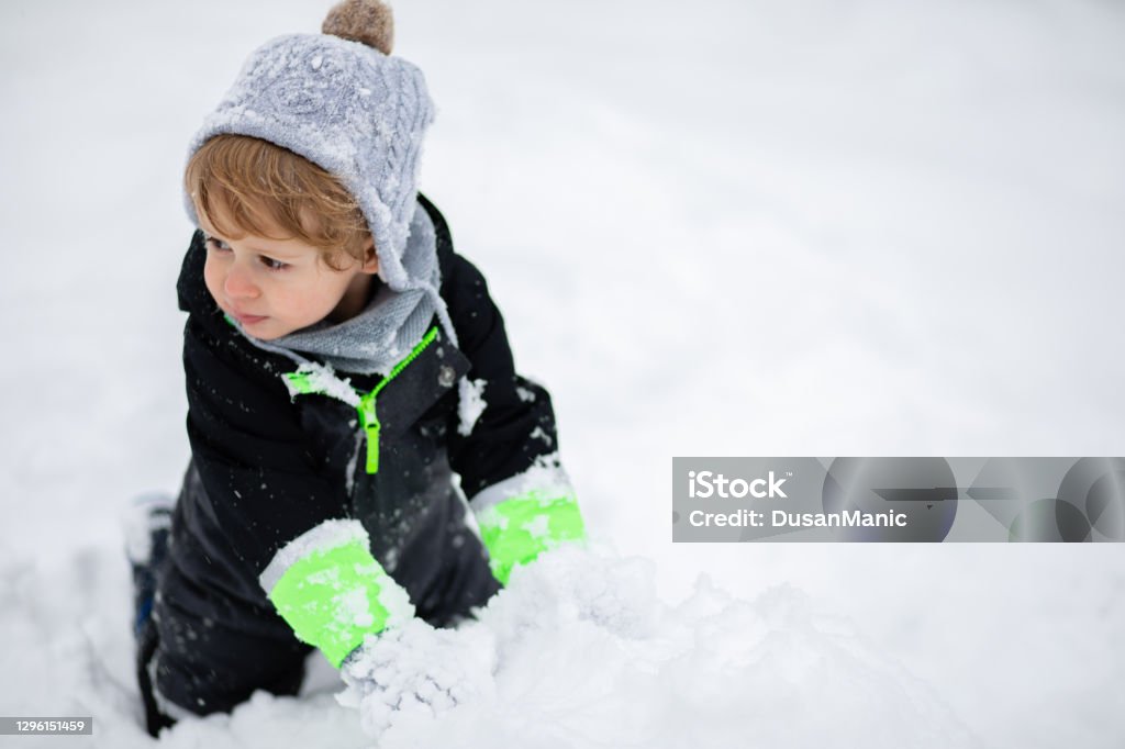 Un Niño Rueda Maneja La Bola De Nieve Juegos Con La Nieve Bebé En Mono  Brillante Y Gorra De Lana Foto de stock y más banco de imágenes de Abrigo  de invierno 