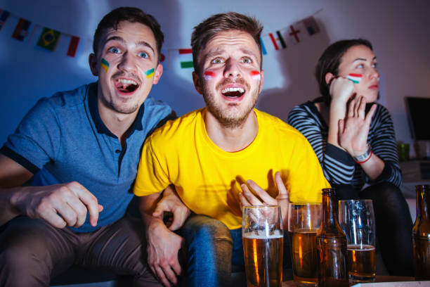 istock Men watching football match at home while girlfriend is bored 1296153364