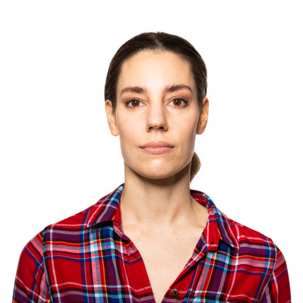 Portrait of a young woman wearing plaid shirt Portrait of a young woman wearing plaid shirt looking at camera.  Caucasian female standing against white background. no emotion stock pictures, royalty-free photos & images