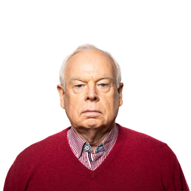 Portrait of a senior man staring at camera. Mature man wearing red sweater standing against white background.