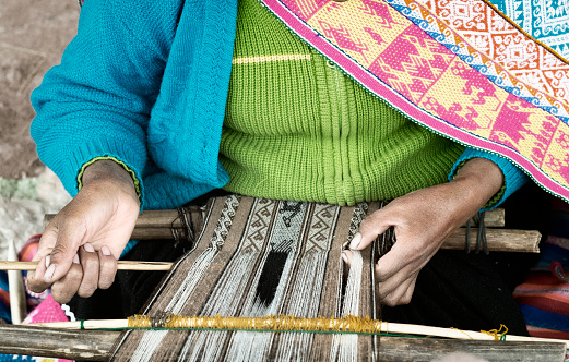 Native Peruvian Woman Weaving Intricate Llama Wool Garments Using A Traditional Hand Loom