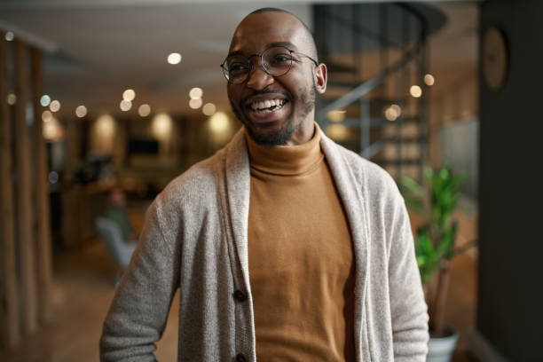 Portrait of creative trendy black african male designer laughing Happy portrait of african entrepreneur laughing and smiling. feeling excited and positive. Wearing trendy clothing and eye glasses in a modern working space black people stock pictures, royalty-free photos & images