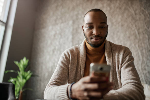 istock Black african business man looking down reading texts on mobile phone 1296158952