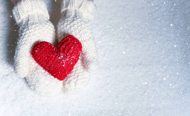 mani femminili in guanti a maglia con cuore rosso sullo sfondo della neve - glove winter wool touching foto e immagini stock