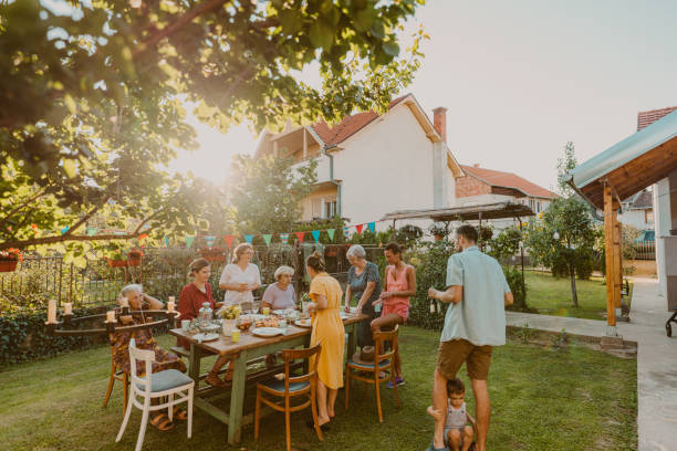 An outdoors family party Photo of multi generation family, having party in the backyard. It's a post covid gathering, out in the open to protect an elderly members of the family. garden parties stock pictures, royalty-free photos & images