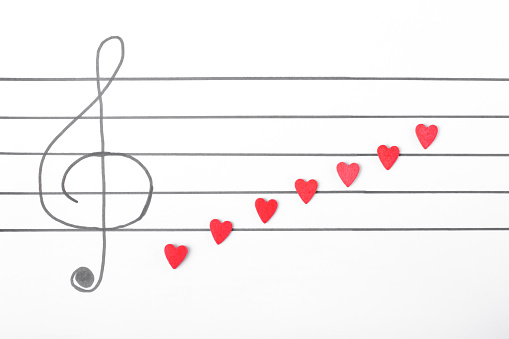 Sugar hearts on the musical staff with treble clef. Music Valentine background. Creative composition