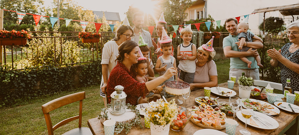 Photo of multi generation family, having a birthday party in the backyard. It's a post covid gathering, out in the open to protect an elderly members of the family.