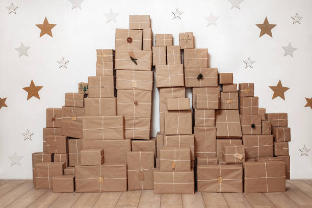 Big stack with paper vintage gift boxes on the wooden floor decorated with star on the white wall