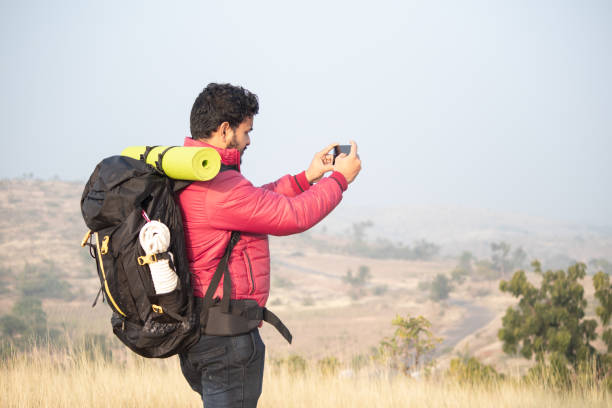 istock Young Traveler with backpack taking picture of landscape using Mobile camera on top of Mountain - concept of travel and adventure photography while trekking. 1296163149