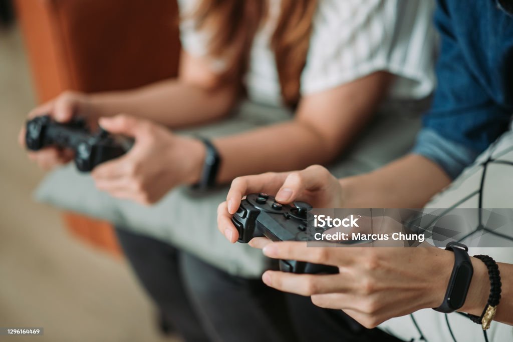 Asian chinese smiling sibling playing video games at home crop shot of two young adults hand holding game joystick Game Controller Stock Photo